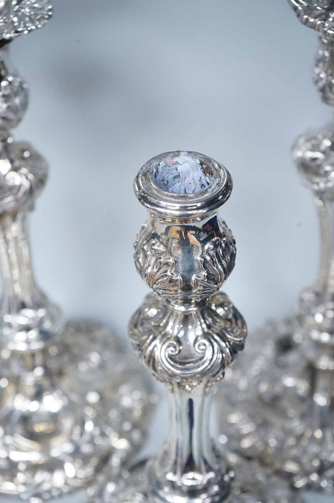 Two similar pairs of George III silver candlesticks, both with fluted tapered columns and decorated with foliage and scrolls, fixed sconces, makers mark rubbed, Sheffield, 1814 and S.C. Younge & Co, Sheffield, 1816, 28.5